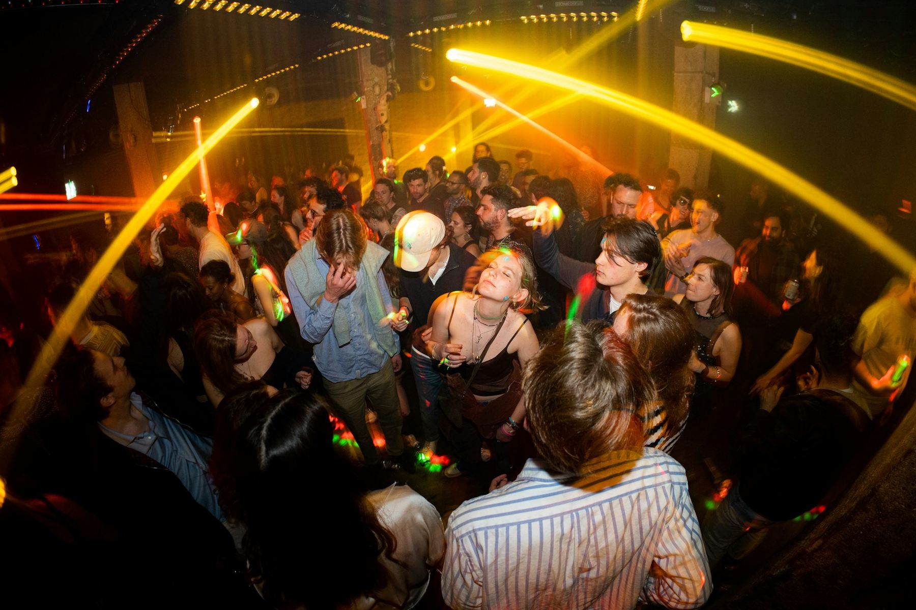 A crowd dancing under yellow club lights